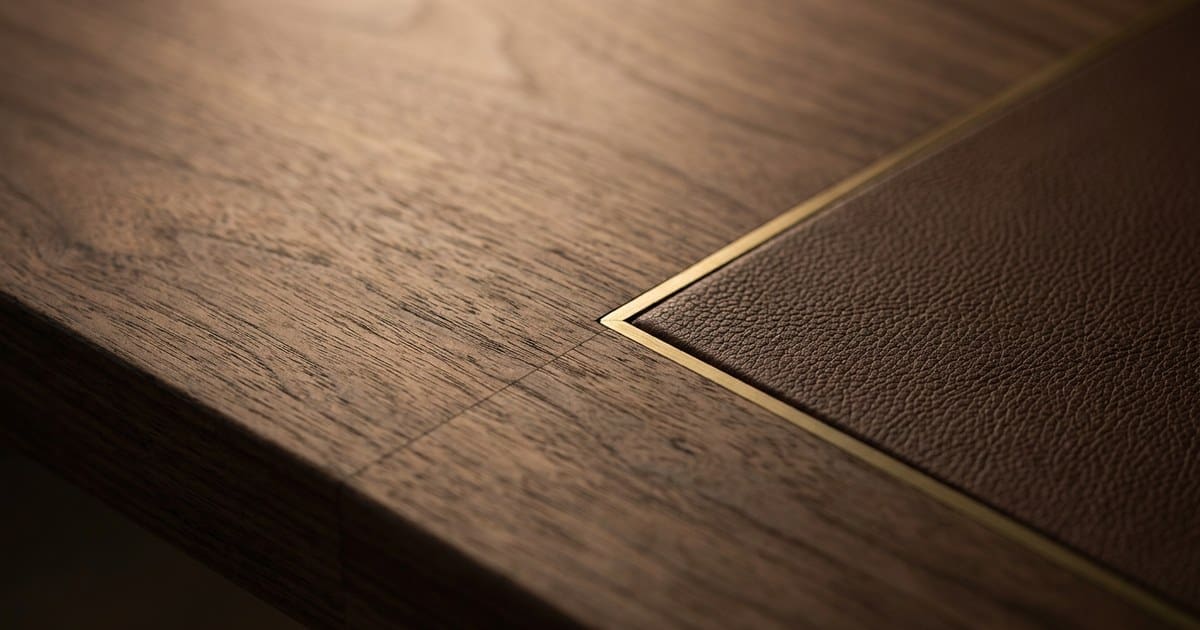 fixed cost blended rate Close-up of a walnut wood surface with a brass inlay strip and leather edge