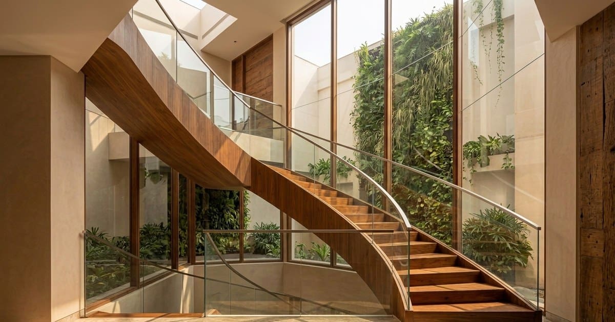 Wood-and-glass staircase rising through a light-filled atrium with a living wall visible beyond. agency deadline missed